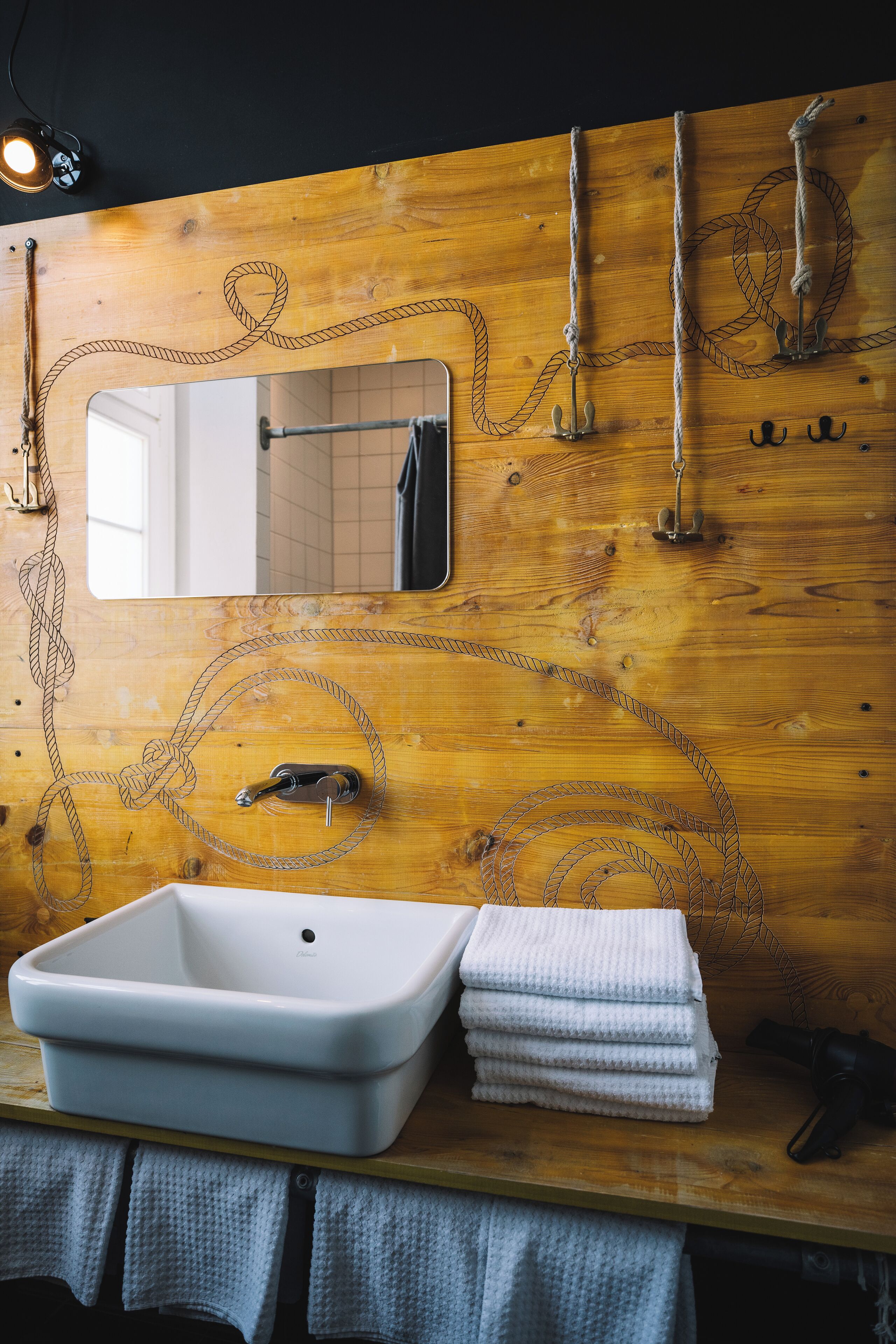 A bathroom with a wooden vanity, a white sink, and a mirror.