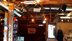 A rustic interior with a 'Welcome' sign, a 'Check In' sign, and various items for sale. - Canyon Motel and RV Park (Williams)