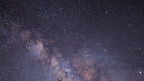 A lodge with a stone facade, wooden balcony, and a clear view of the Milky Way. - Canyon Motel and RV Park (Williams)