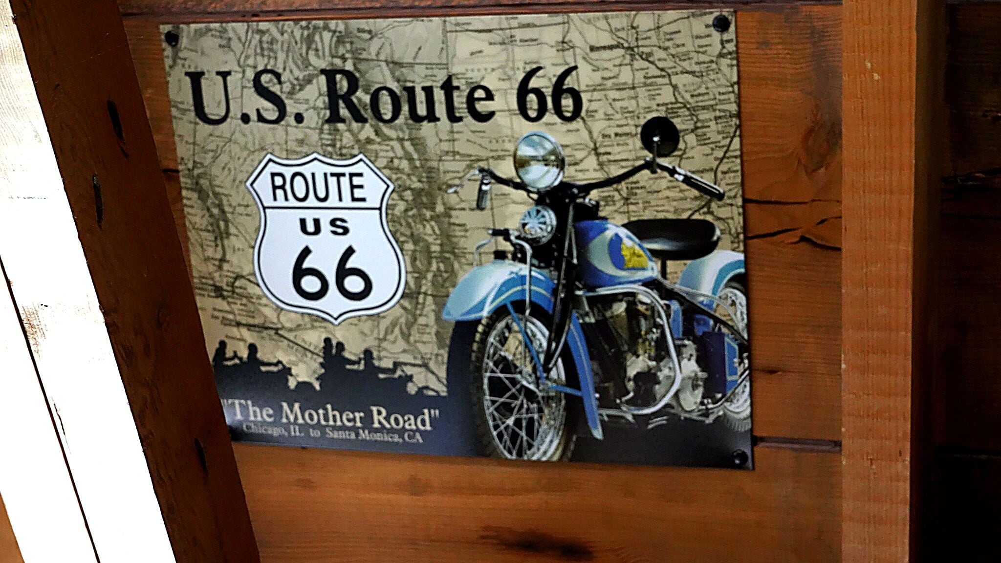 Un panneau indiquant l’itinéraire de la route américaine 66, orné d’une illustration de moto d’époque et du texte « The Mother Road », reliant Chicago, dans l’Illinois, à Santa Monica, en Californie.