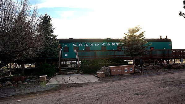 A green building labeled "GRAND CANY" with a wooden deck and a trash bin.