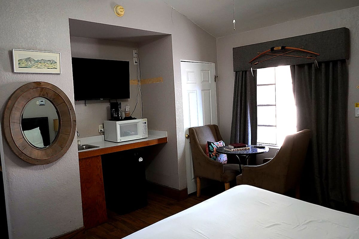 Ein Hotelzimmer mit Bett, Schreibtisch mit Mikrowelle, Stuhl, Fernseher und einem Fenster mit Vorhängen.