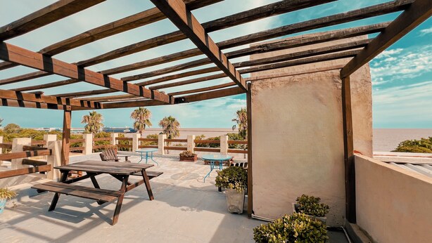 Un patio al aire libre con muebles de madera y plantas en macetas.