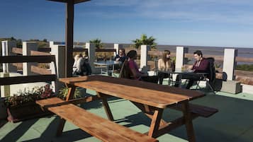 Enjoy ocean views from this patio with a picnic table and benches surrounded by lush greenery.