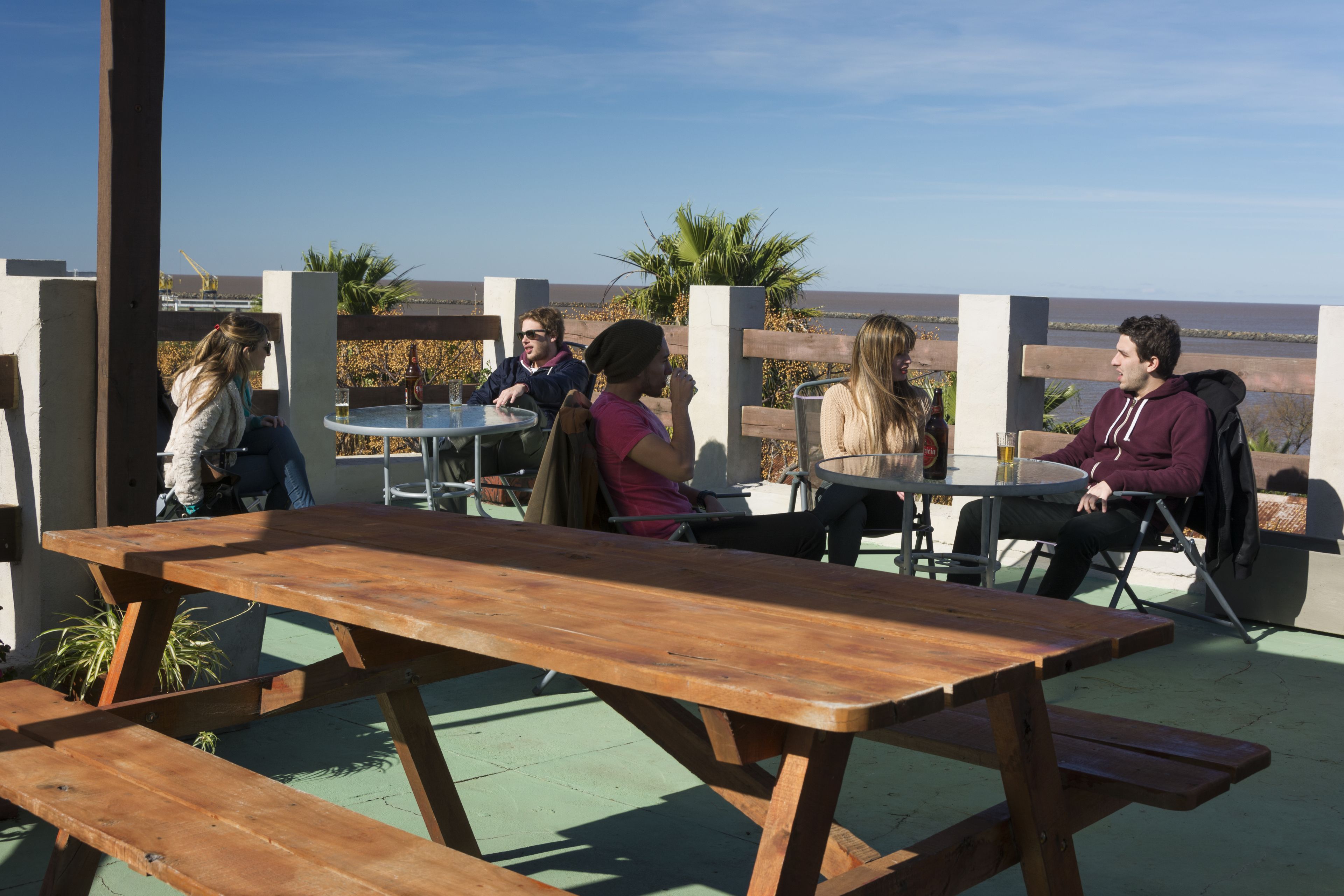 A group of people seated at an outdoor table with a view of the ocean.