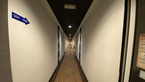 A long, narrow hallway with white walls and wooden flooring, leading to a door with a sign on the wall indicating room numbers 3041-3098.