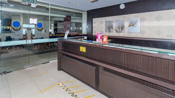 A reception desk with a glass partition, a clock, and a sign indicating a 10% cash back offer.
