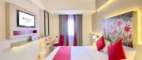 Una habitación de hotel con una cama, televisión, escritorio y un cuadro.