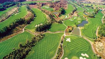 Vista aérea de un campo de golf con varios greens, bunkers de arena y obstáculos acuáticos.