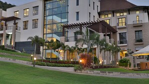 Un hotel moderno con varios pisos, amplias ventanas y un jardín bien cuidado.