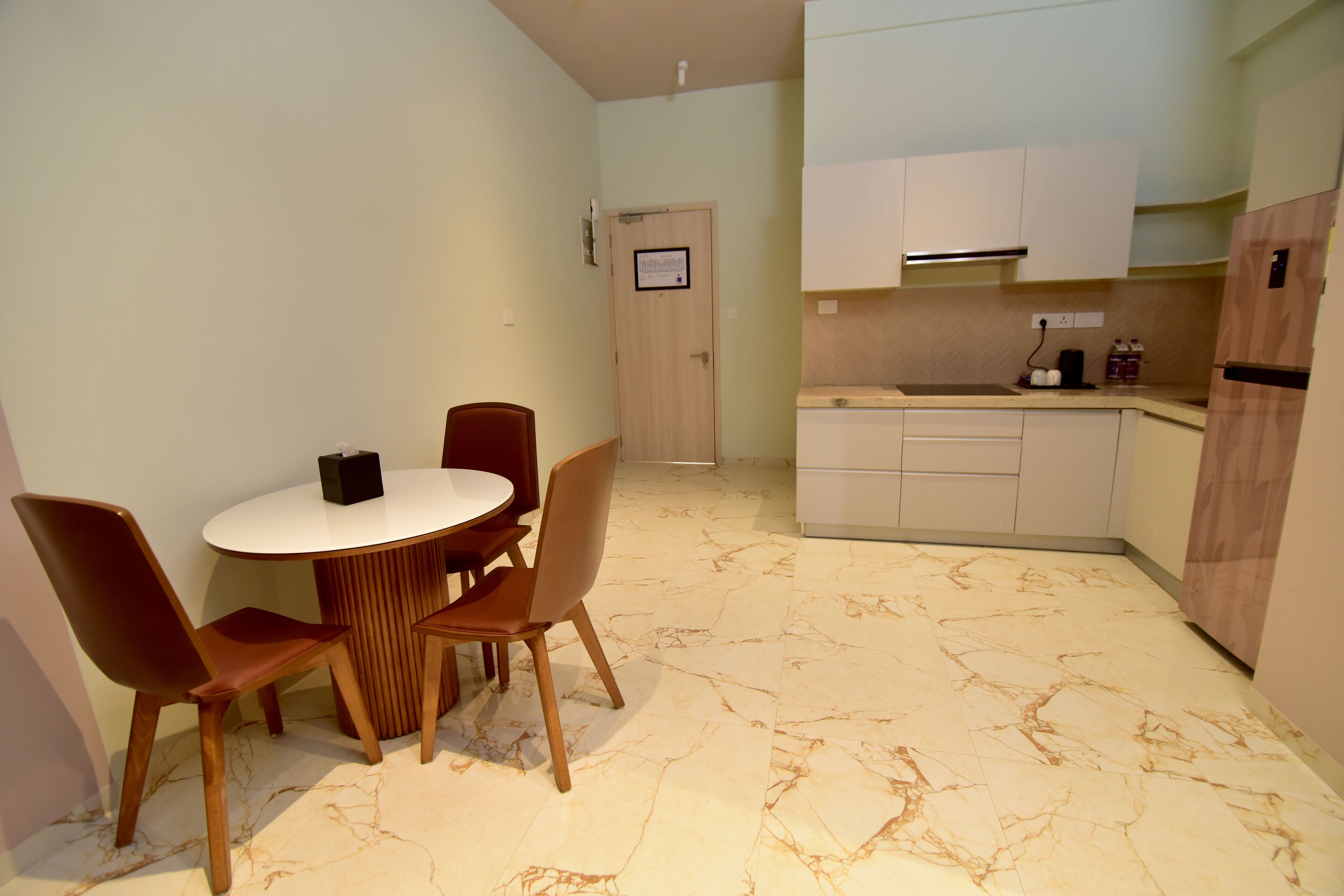 Una cocina compacta con zona de comedor. Incluye una mesa redonda con cuatro sillas, un horno empotrado y un microondas.