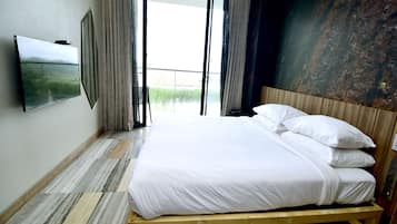 A hotel room with a large bed, a flat-screen TV, and a view through the open door.