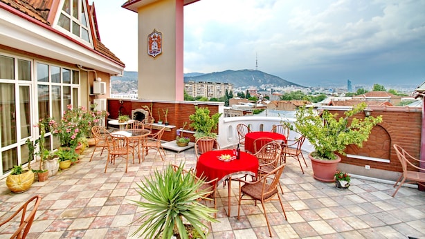 Una terraza en la azotea con mobiliario exterior, plantas en macetas y vistas a la ciudad.