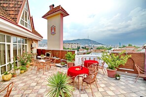 A rooftop terrace with outdoor seating, potted plants, and a view of the cityscape. - Hotel Irmeni (Tbilisi)