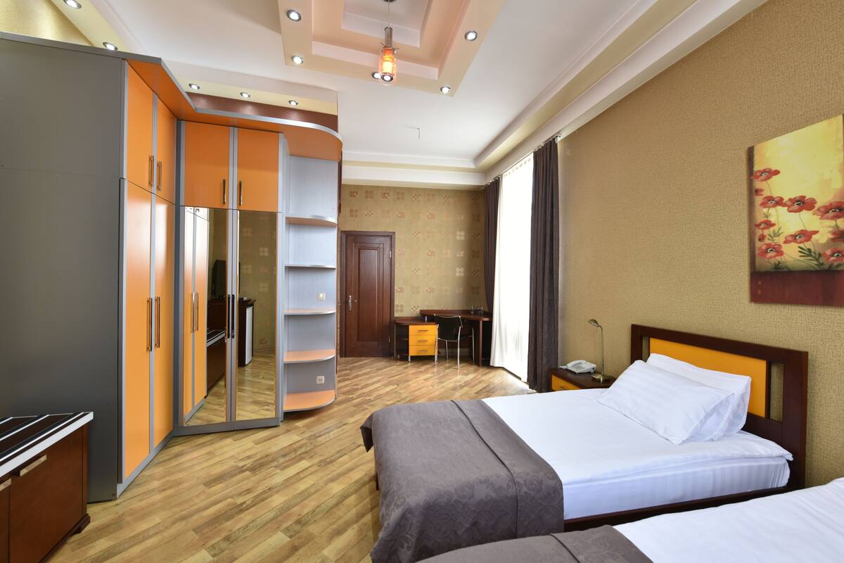 A hotel room with a bed, a desk, a wardrobe, and a mirror.