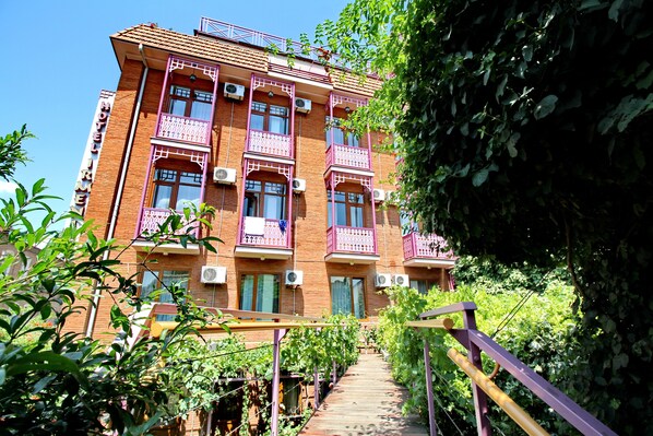 A multi-story brick building with balconies and air conditioning units. - Hotel Irmeni (Tbilisi)