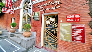 Un hotel con fachada de ladrillo rojo, un letrero que indica que es el “Hotel Irmeni”, y un cartel grande con texto en un idioma extranjero.