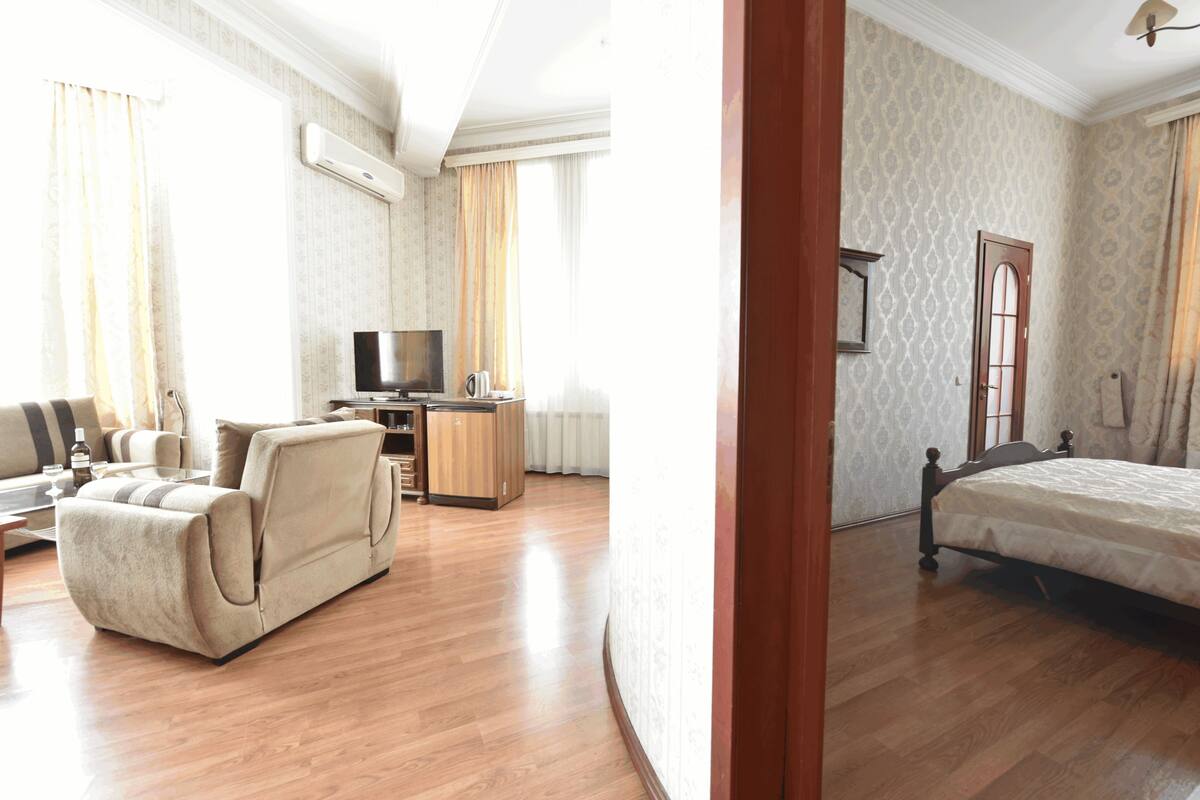 A hotel room with a bed, a sofa, a TV, and a desk.