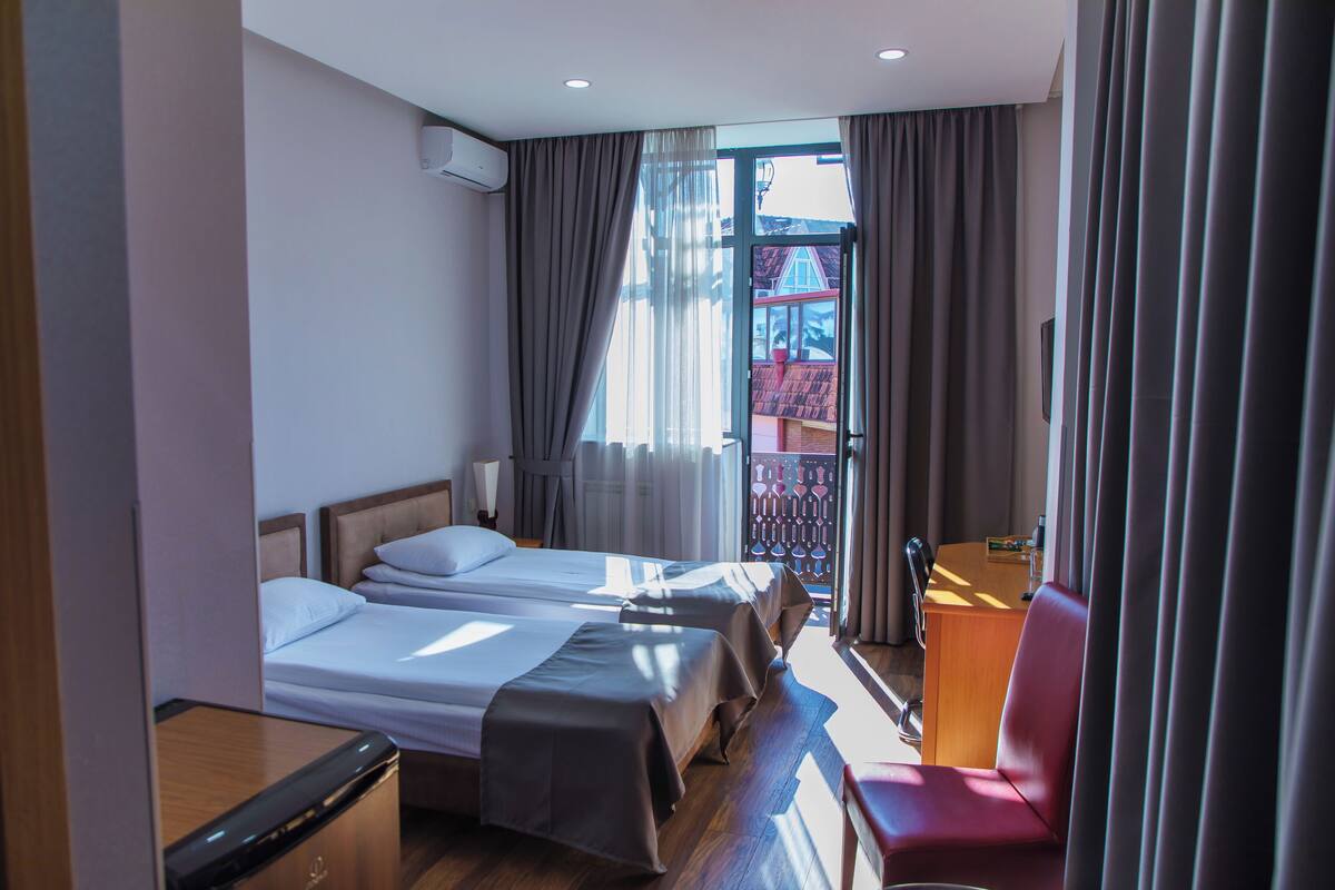 A hotel room with two beds, a desk, and a chair.