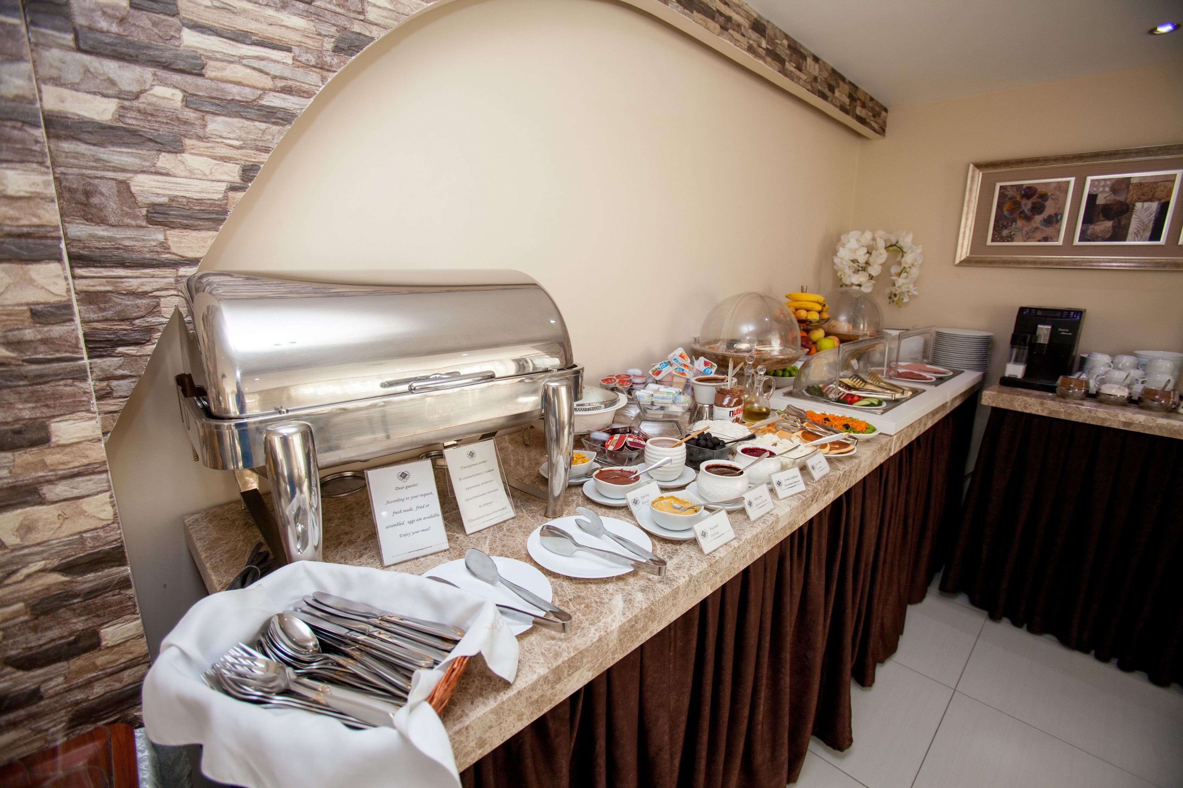 A buffet setup with a self-service grill, various food items, and utensils.