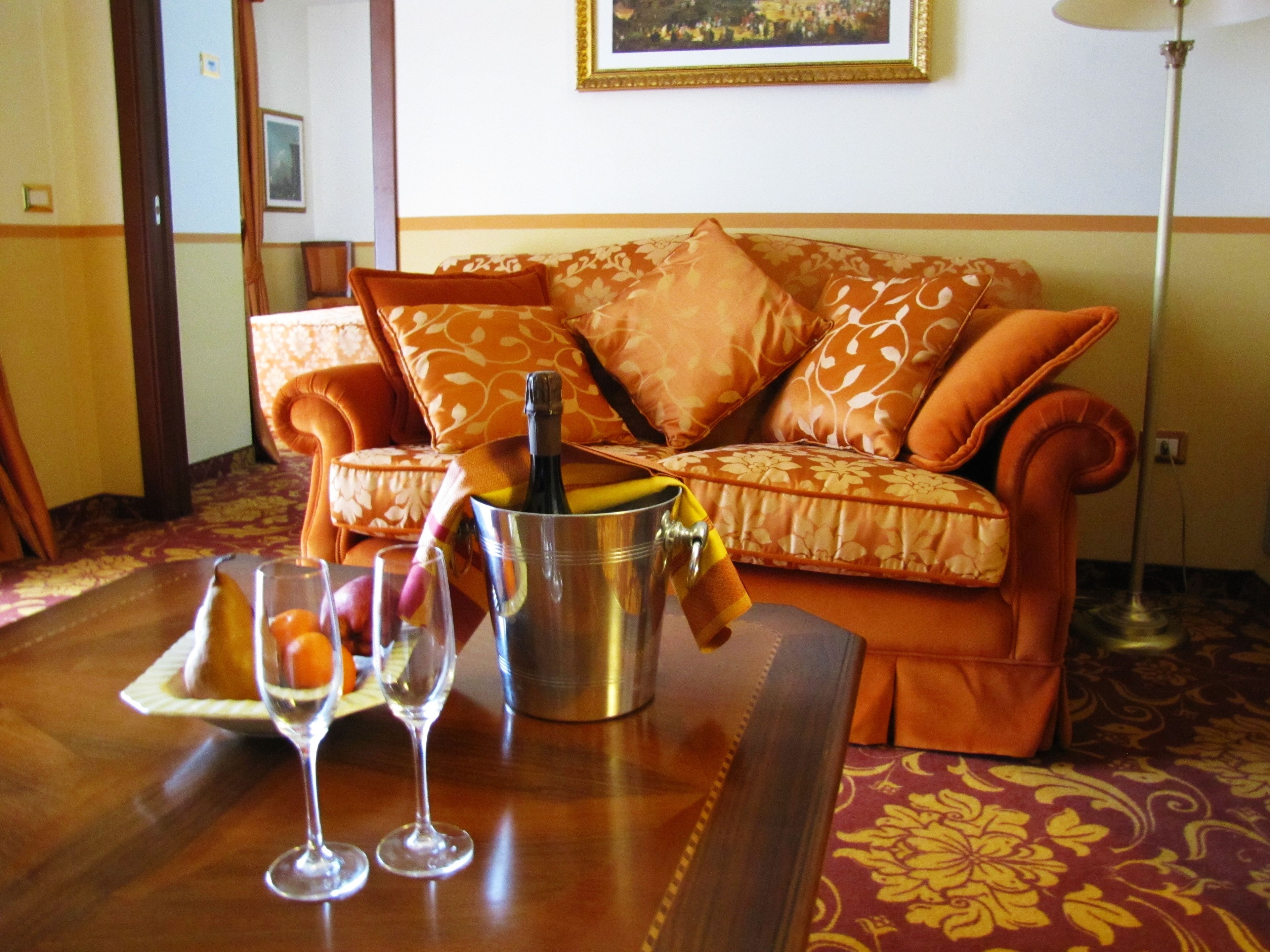 Une pièce avec un canapé, une table sur laquelle se trouvent une bouteille et des verres, et un tapis à motifs.
