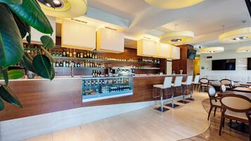 A modern bar area with a wooden counter, shelves of liquor bottles, and seating for guests.