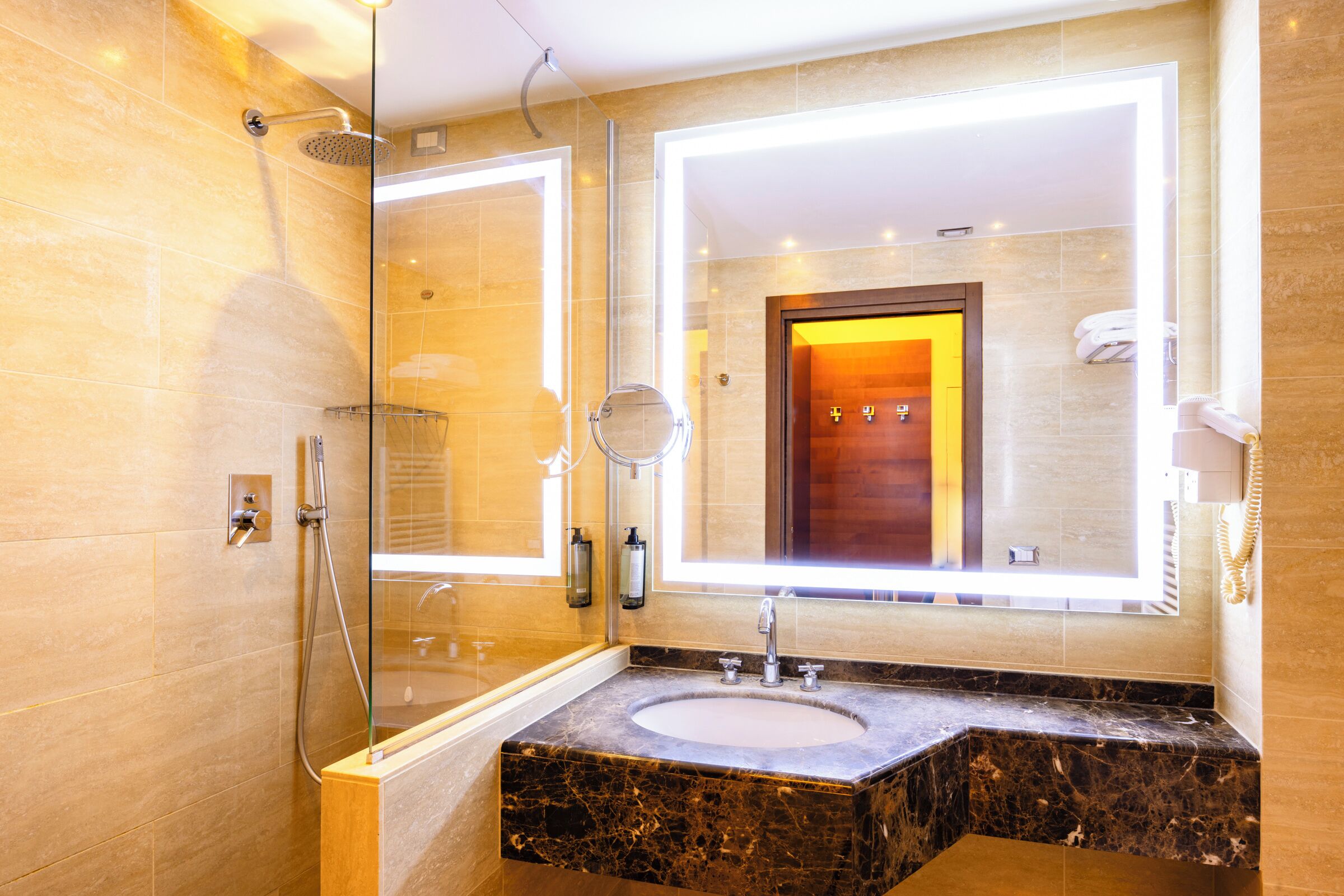 A modern bathroom with a glass-enclosed shower, a marble sink, and a large mirror.