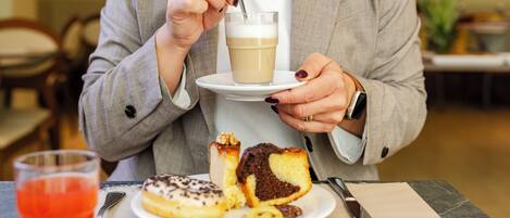 A person holding a cup of coffee and a plate with pastries.