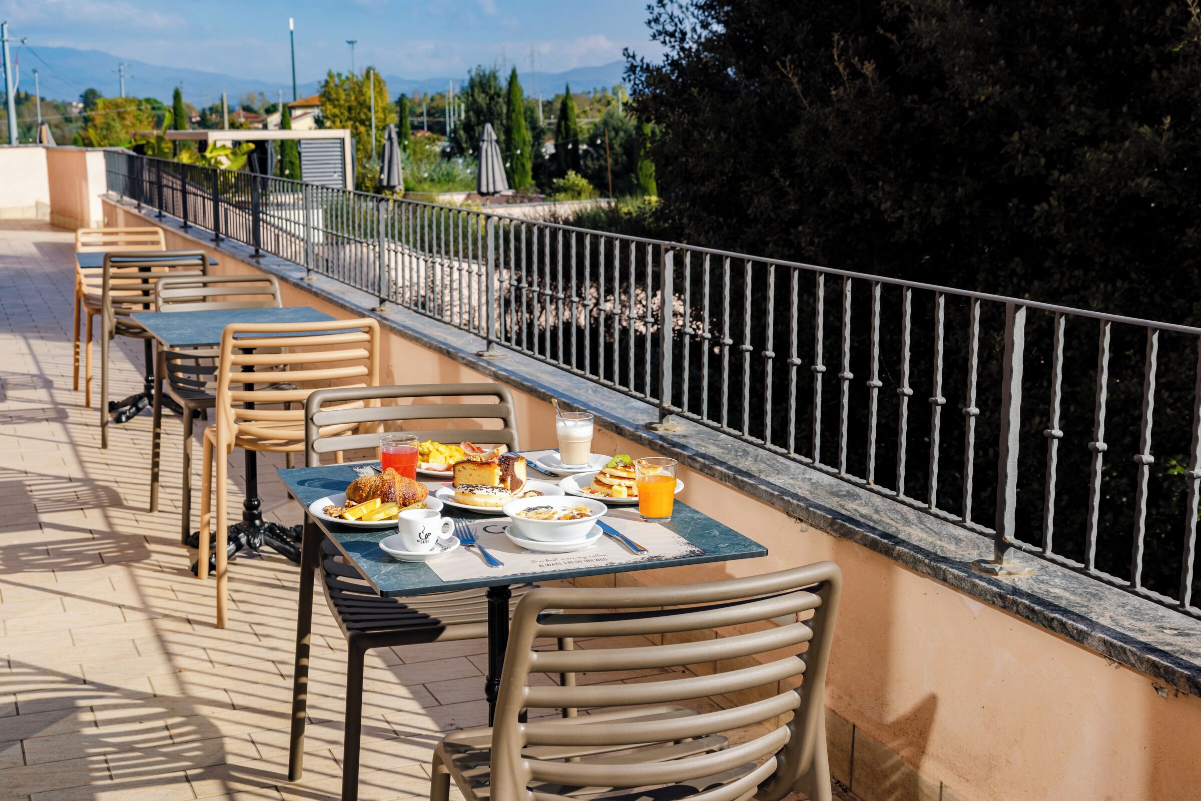 Terraza con mobiliario exterior, incluyendo mesas y sillas, y una barandilla.