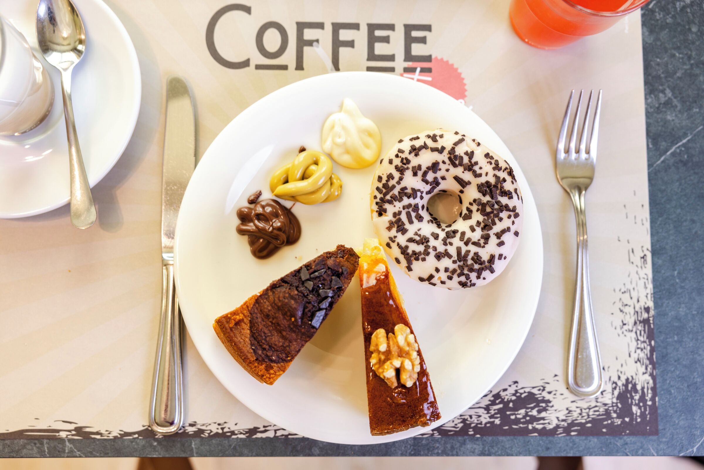 Un plato con diversos postres, incluyendo un pastel de chocolate, un remolino de caramelo, un pretzel cubierto de chocolate y una rosquilla con chispas de chocolate.