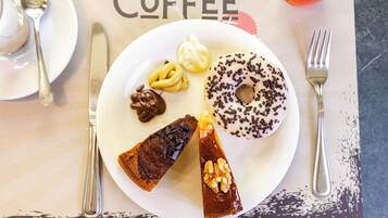 Un plato con diversos postres, incluyendo un pastel de chocolate, un remolino de caramelo, un pretzel cubierto de chocolate y una rosquilla con chispas de chocolate.