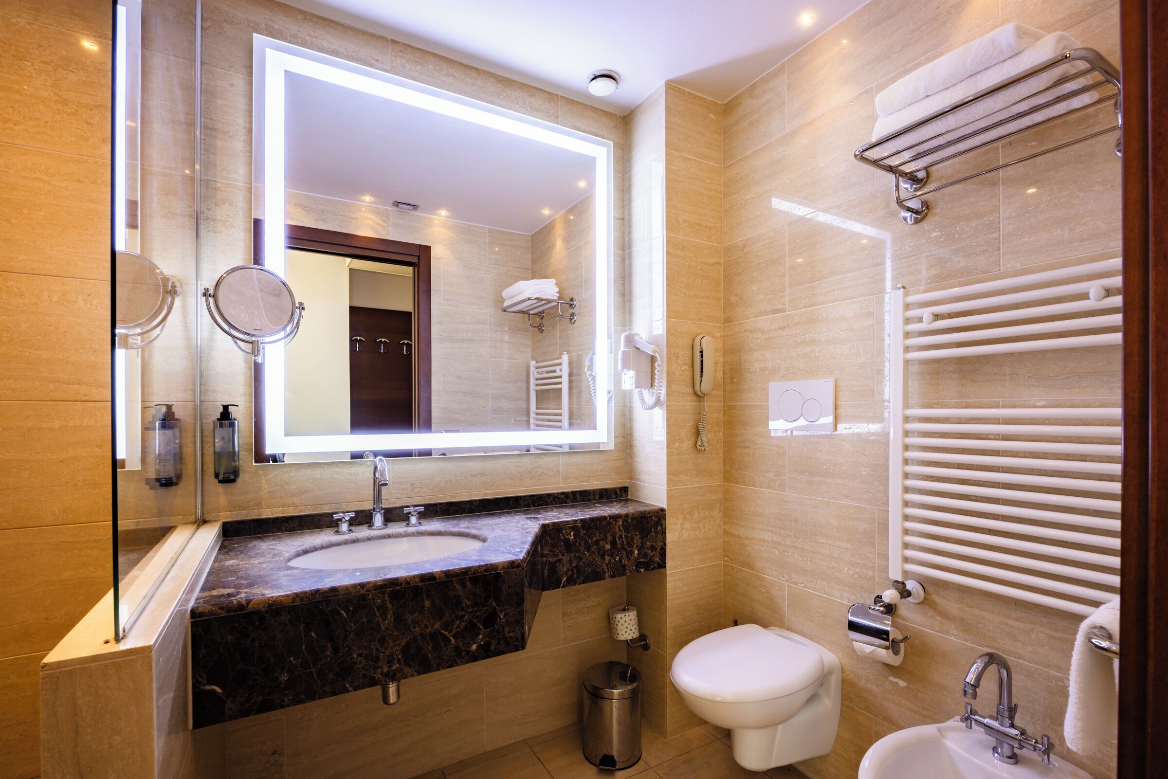 Un baño moderno con un espejo grande, un lavamanos, un inodoro y un bidé.