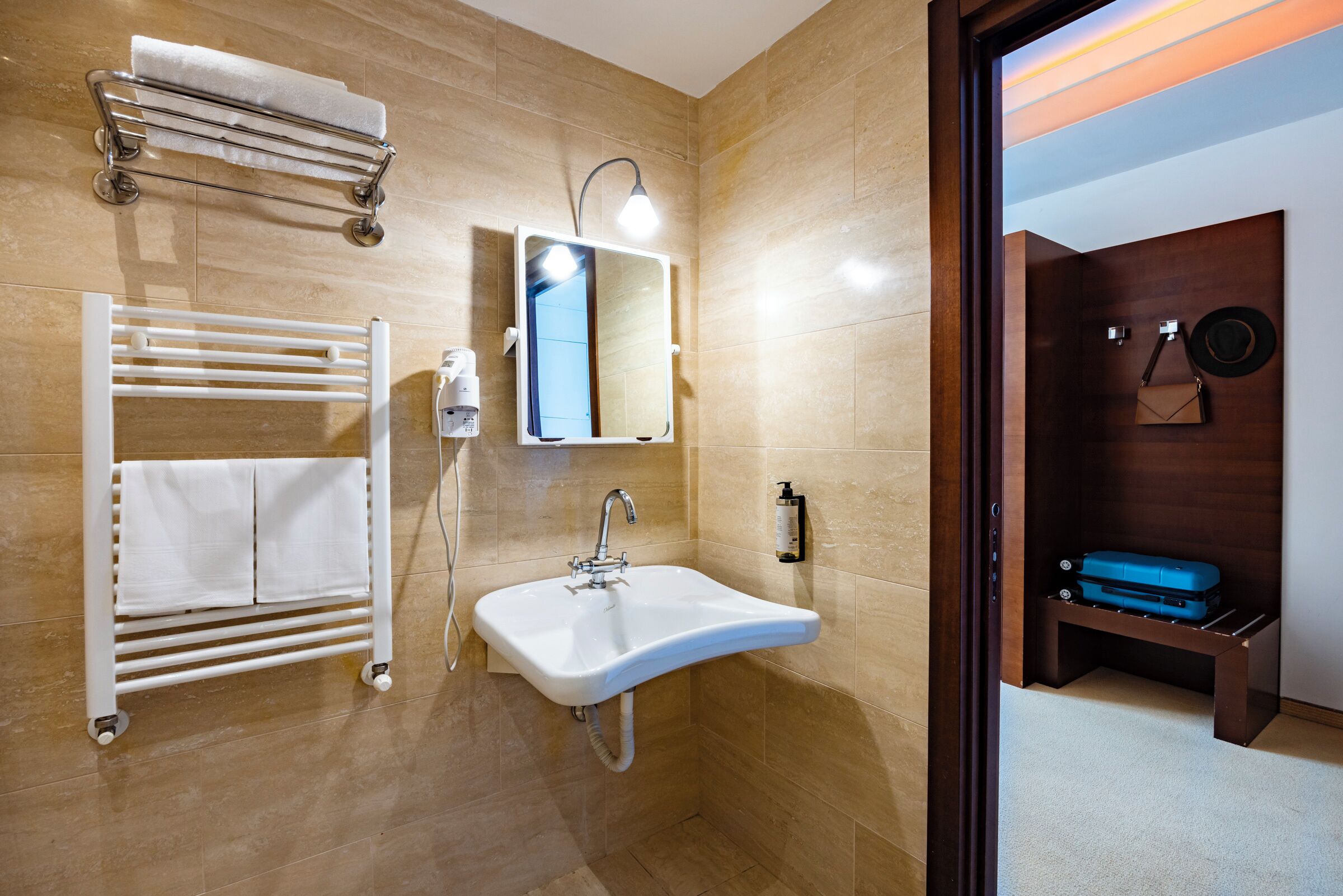 Un baño moderno con lavamanos blanco, toallero y espejo.