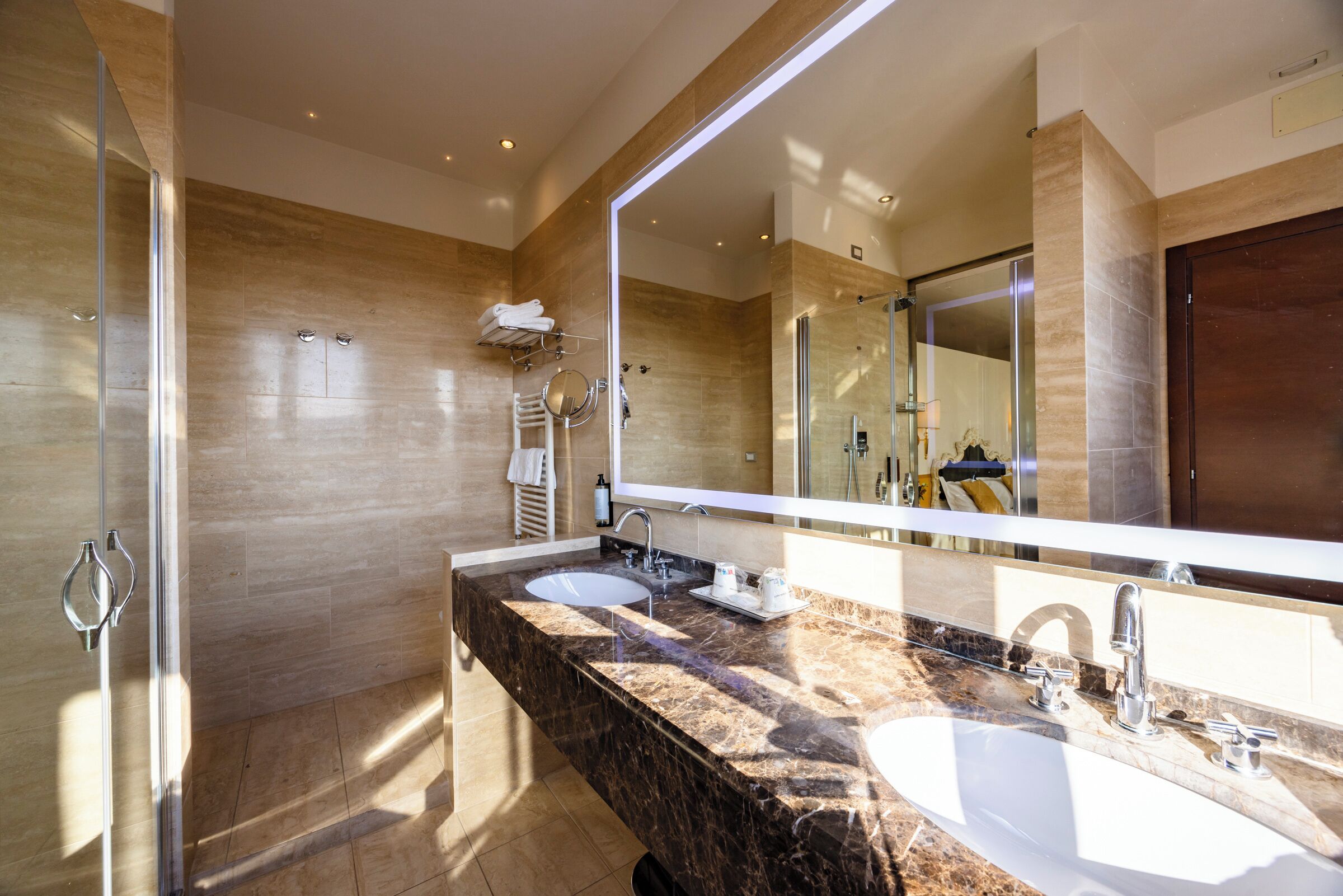 A modern bathroom with two sinks, a large mirror, and a glass shower enclosure.