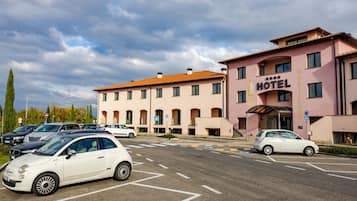 A hotel with a parking lot, multiple cars, and a clear sky.