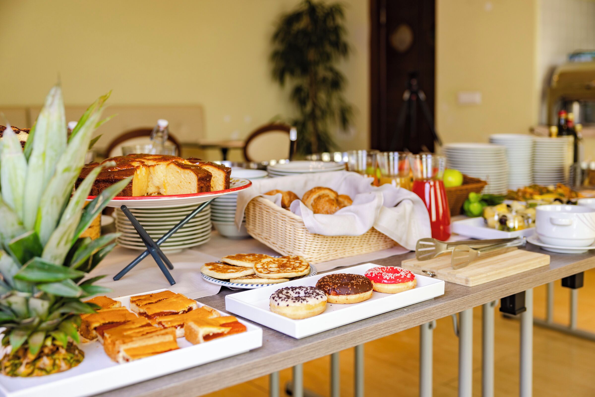 Ein reich gedeckter Buffet mit verschiedenen Backwaren, einer Torte und einer Ananas.