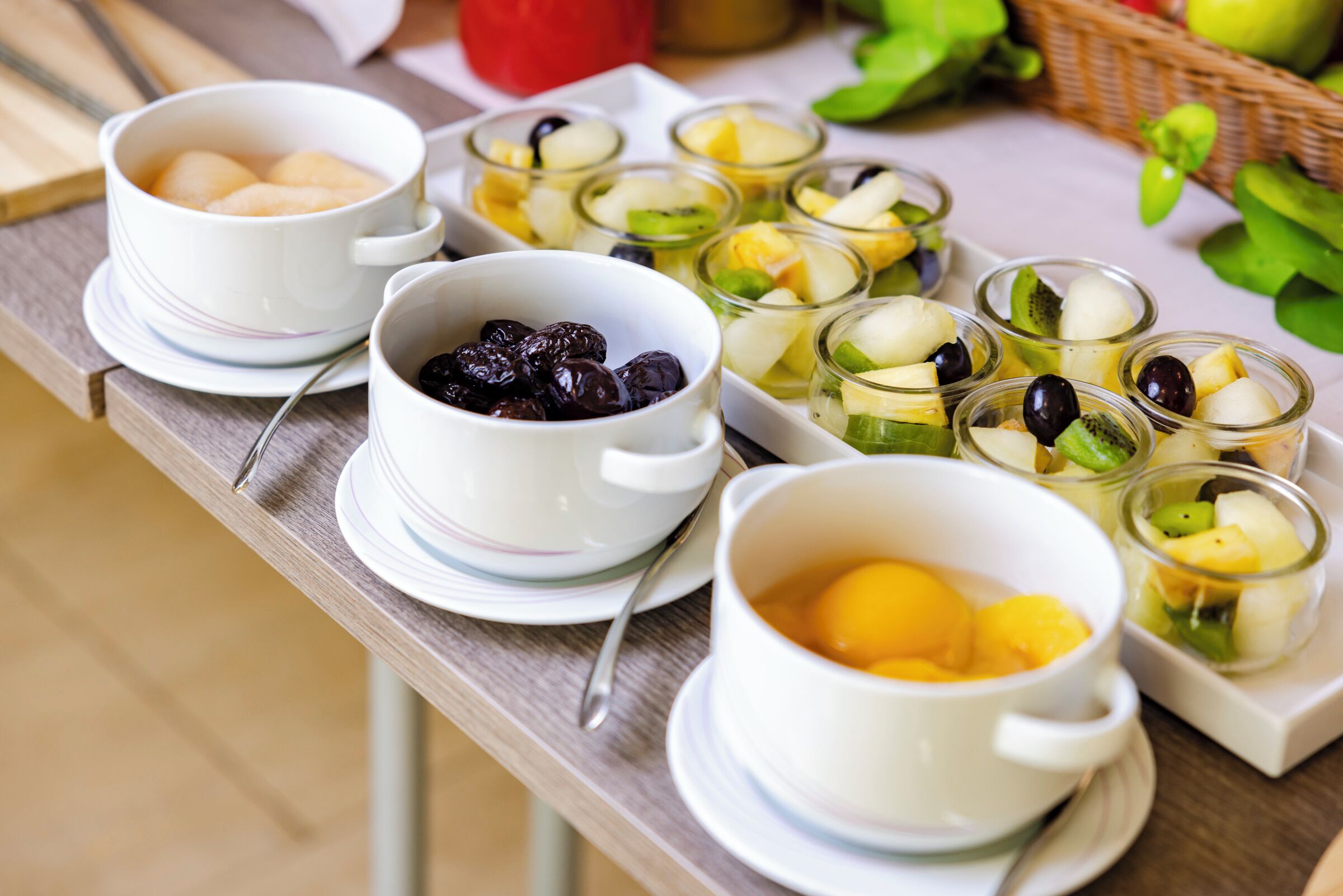 A table with various fruit bowls and cups, likely a fruit salad or snack setup.