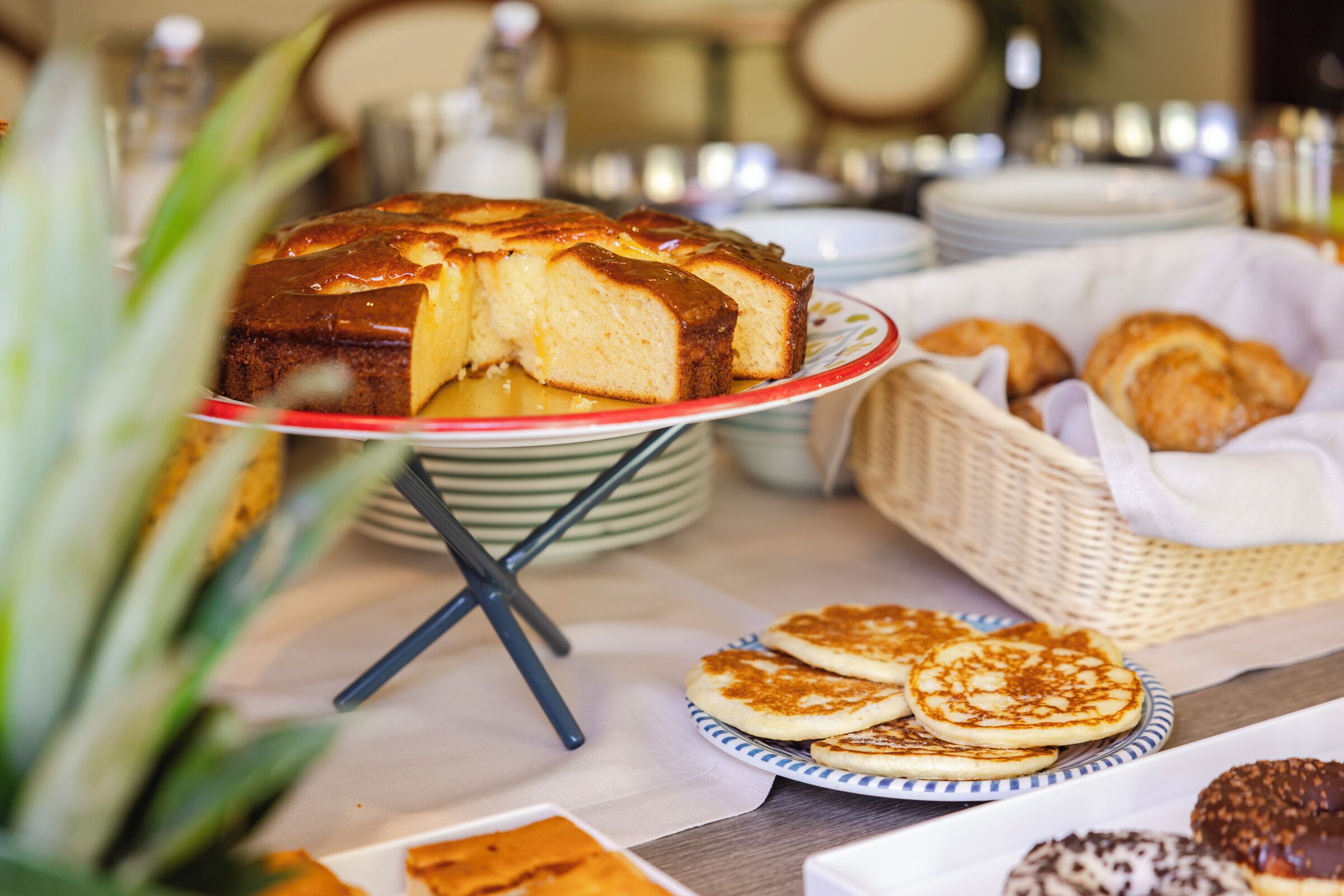 A buffet table with a variety of breakfast items including pancakes, pastries, and a cake.