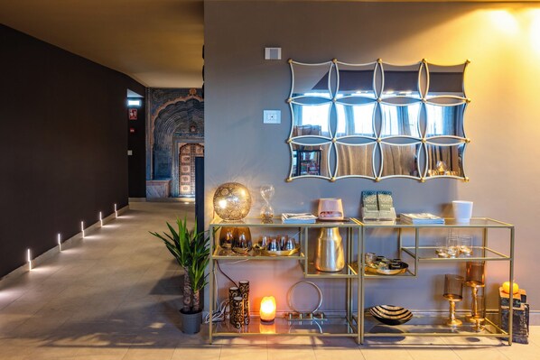 A hallway with a decorative wall, a glass display table with various items, and a patterned wall design.