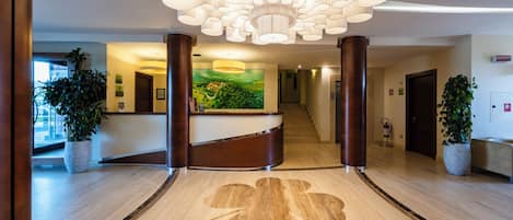 Zona de recepción de un hotel con un mostrador curvo, un mural grande y un diseño de piso único.