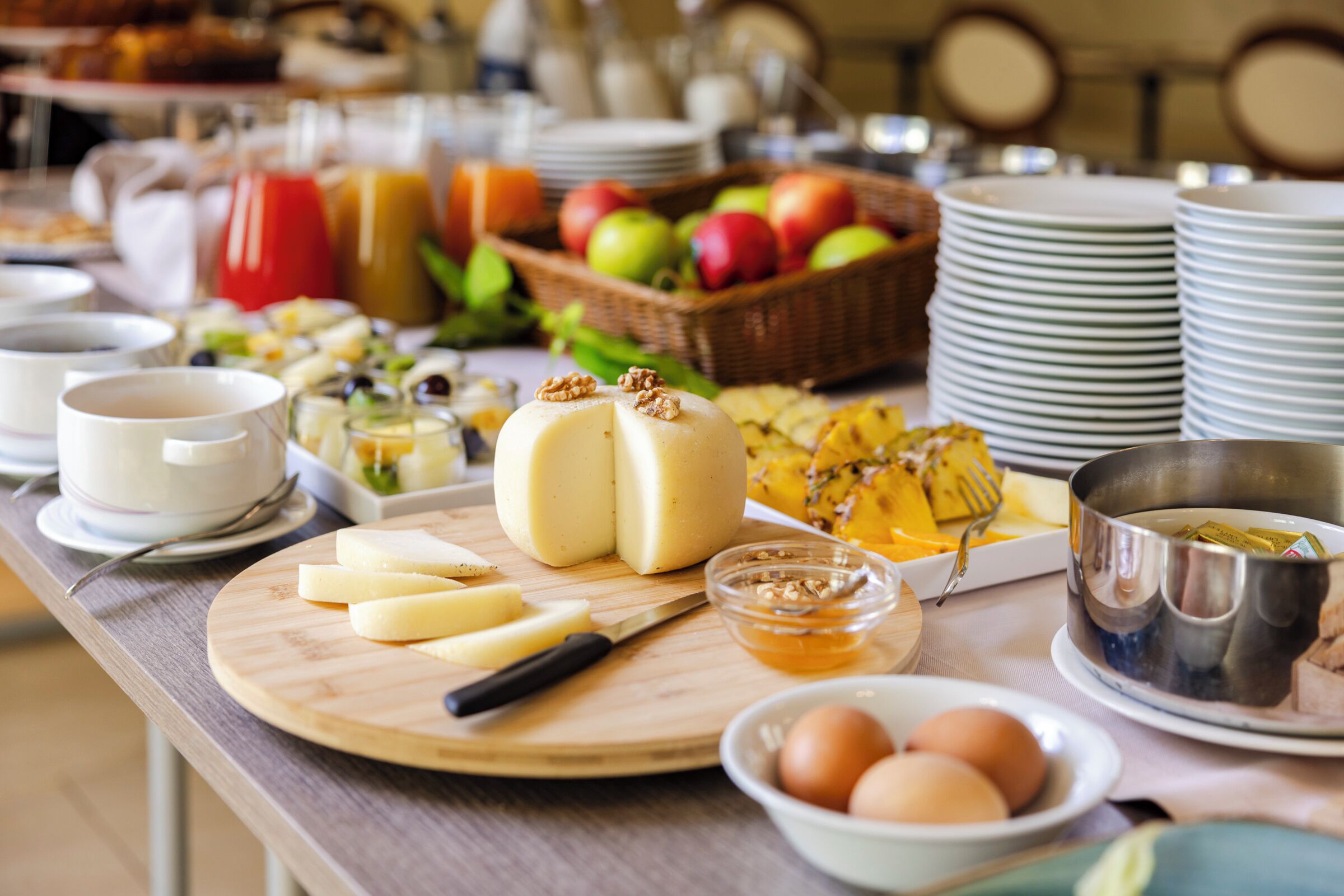 A breakfast buffet with various food items, including cheese, eggs, and fruits.