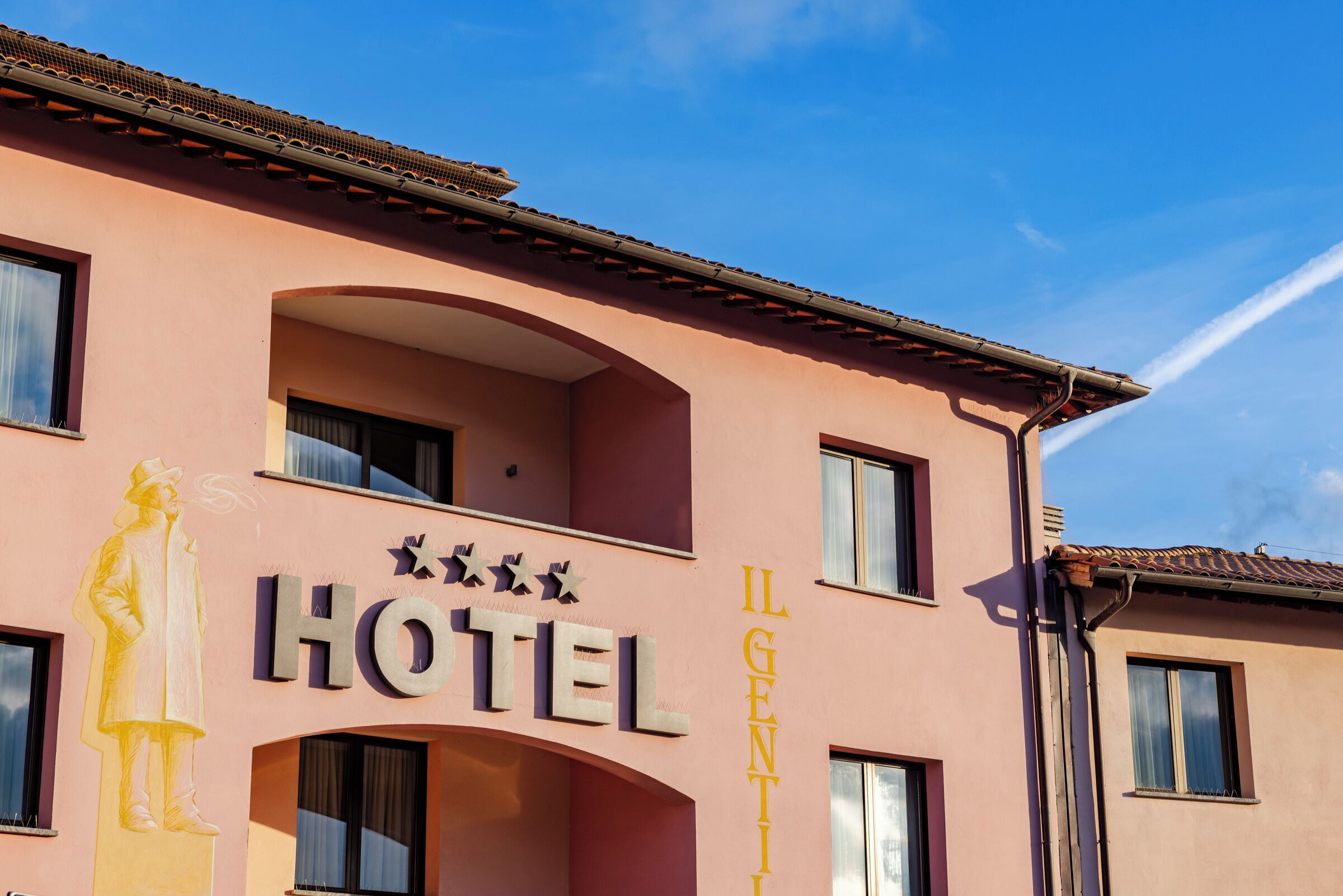 A pink building with the sign "HOTEL" and "IL GENTILLO" on the facade.