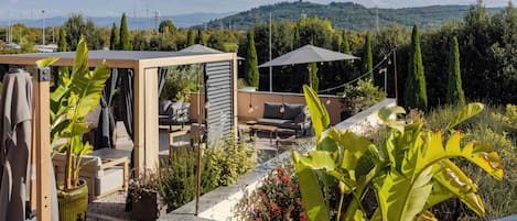 Una terrazza sul tetto con posti a sedere all'aperto, un pergolato e vista sulle colline.
