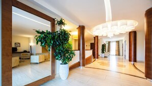A modern hotel lobby with a large mirror, potted plants, and a spacious seating area. - Il Gentiluomo Hotel & SPA (Arezzo)