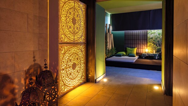 A modern interior with a decorative wall, a bed with pillows, and a small table with a lamp. - Il Gentiluomo Hotel & SPA (Arezzo)