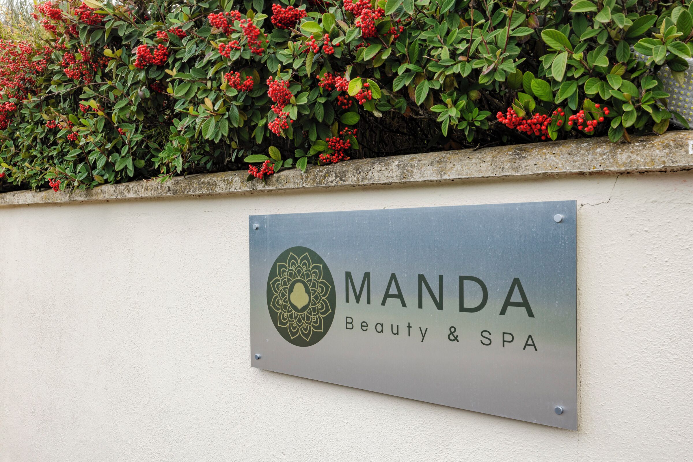 Une enseigne indiquant « Manda Beauty & Spa » est fixée à un mur.