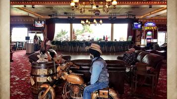 Eine Barbereich mit einem Oldtimer-Motorrad, Ledersitzmöbel und einem Kronleuchter.