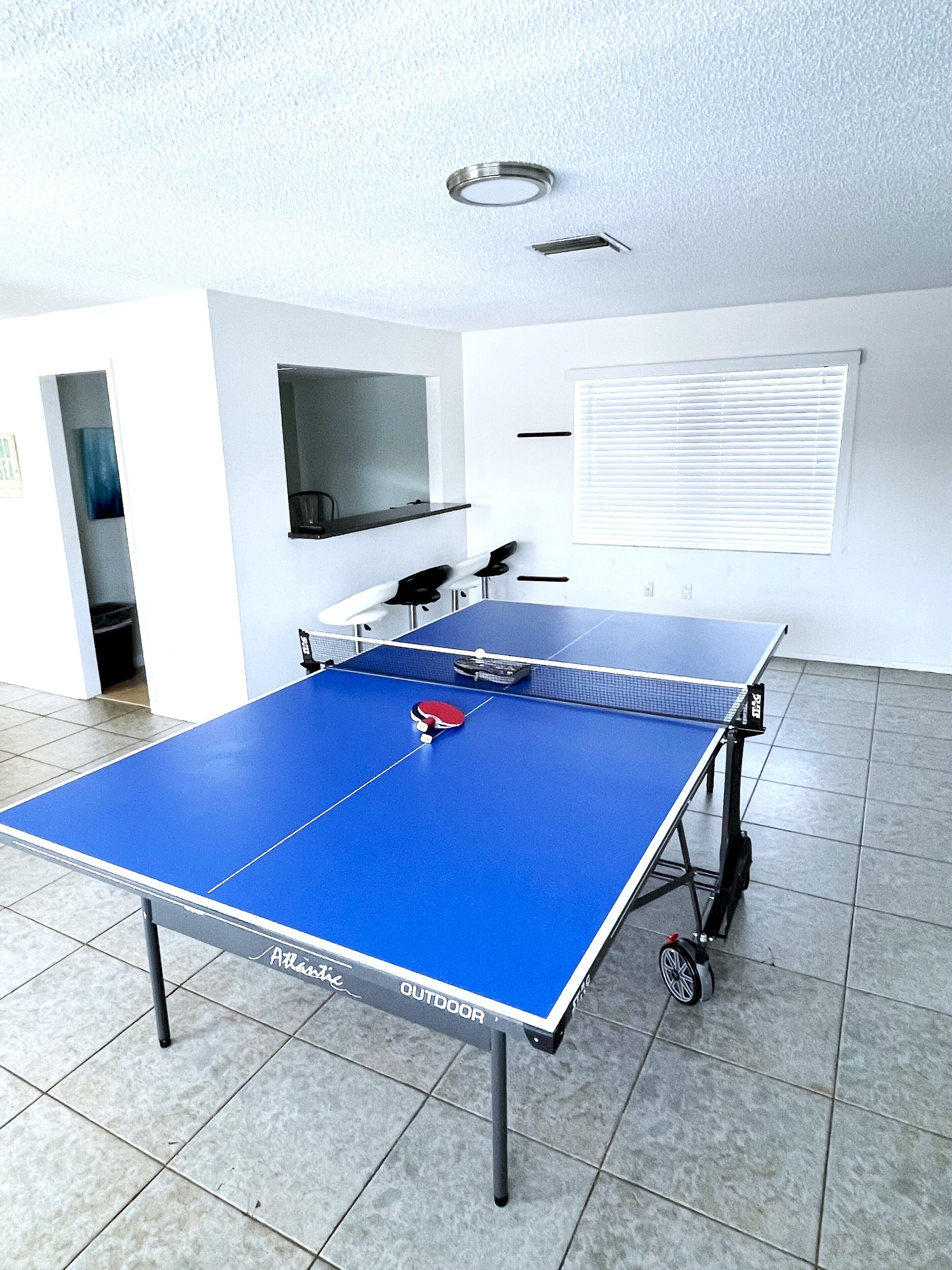 Ein Pingpongtisch mit blauer Spielfläche, einem rot-weißen Schläger und einem schwarzen Tischgestell.