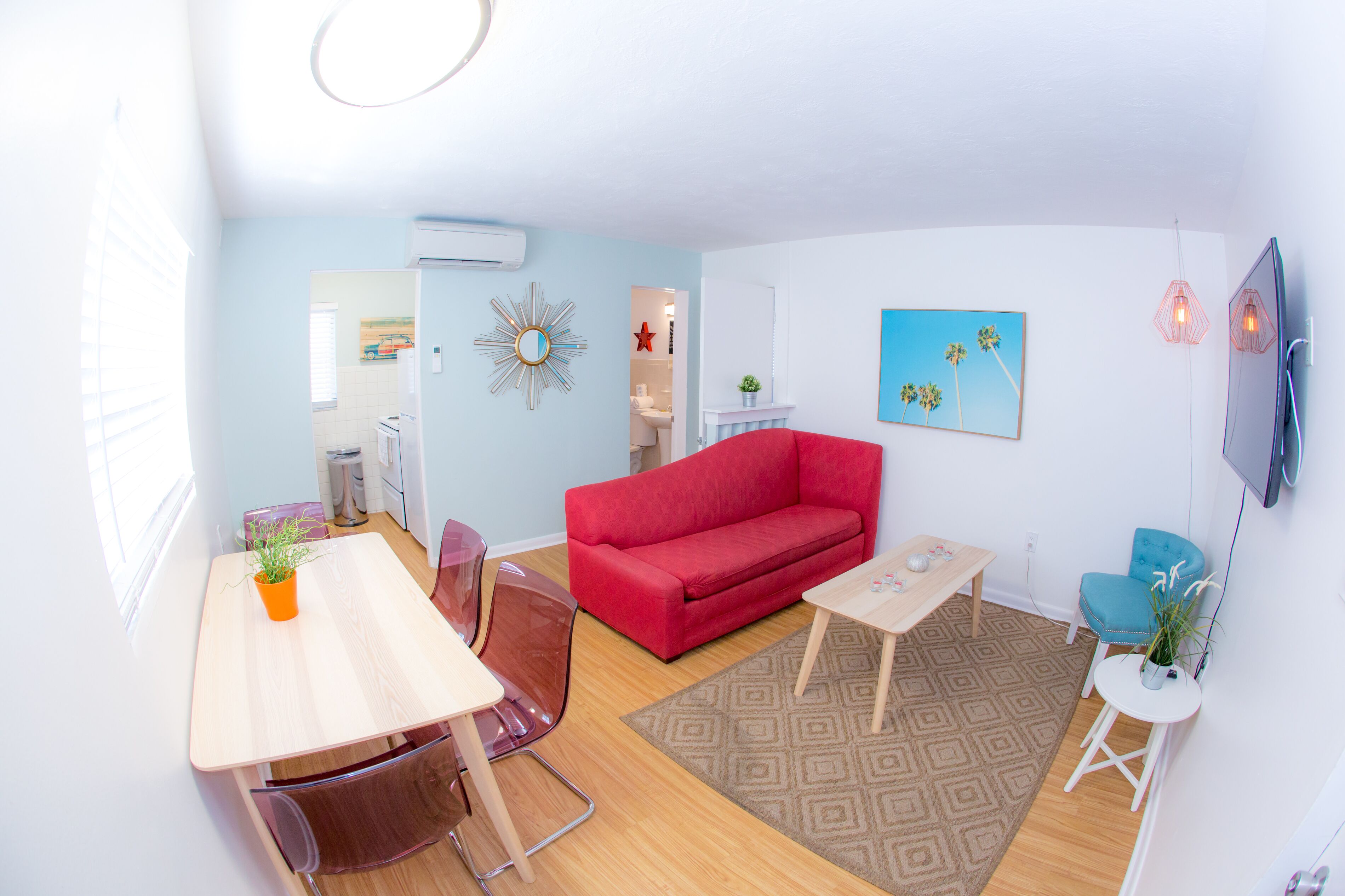 Una sala de estar moderna con un sofá rojo, una mesa de centro de madera y un comedor con una mesa y sillas.