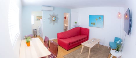 Una sala de estar moderna con un sofá rojo, una mesa de centro de madera y un comedor con una mesa y sillas.